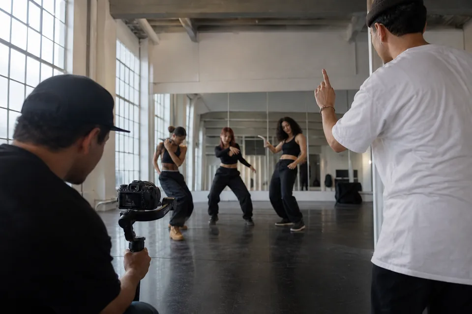 Adult dancers rehearsing choreography for a music video in a mirrored studio